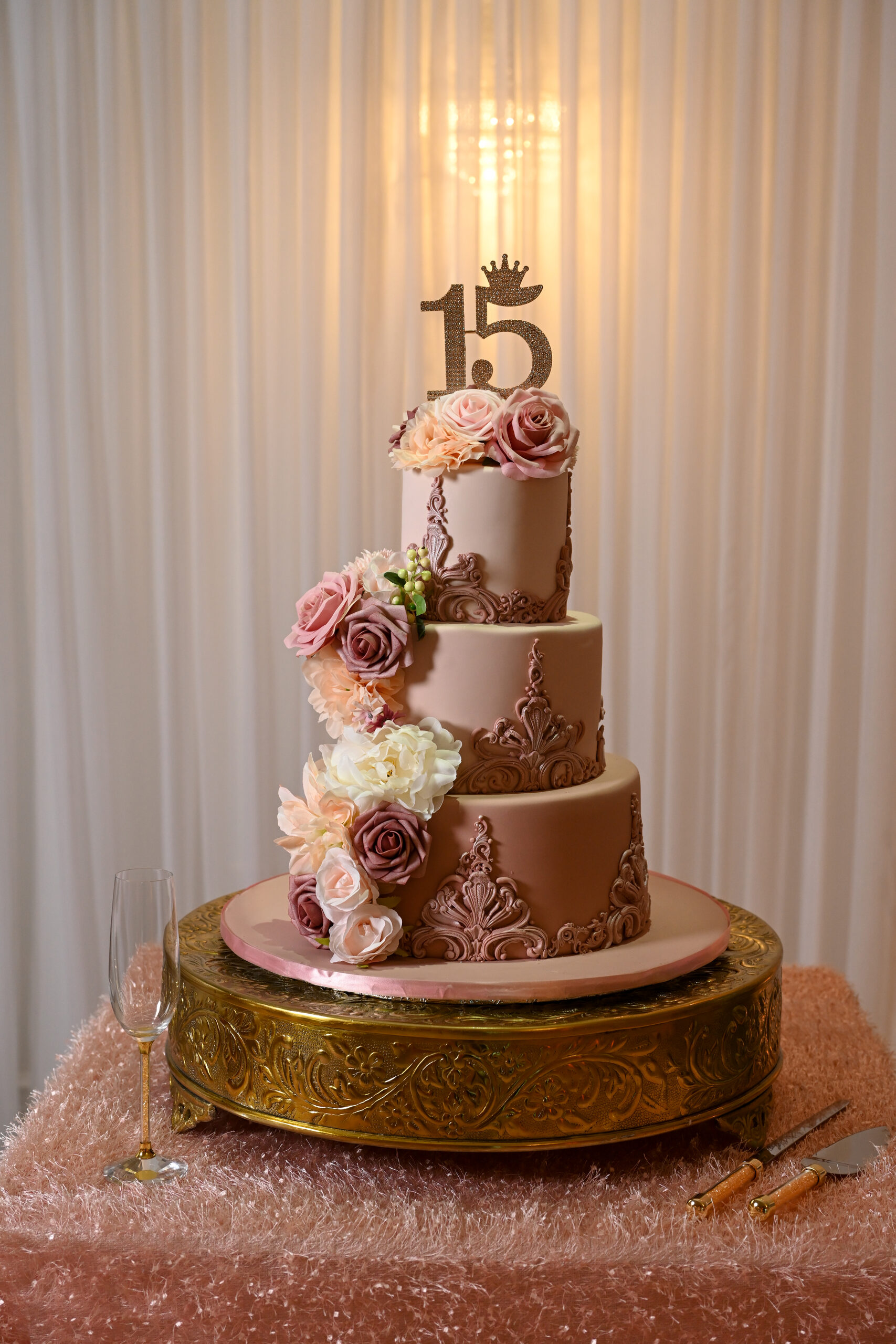 A three-tier quinceañera cake on a gold stand