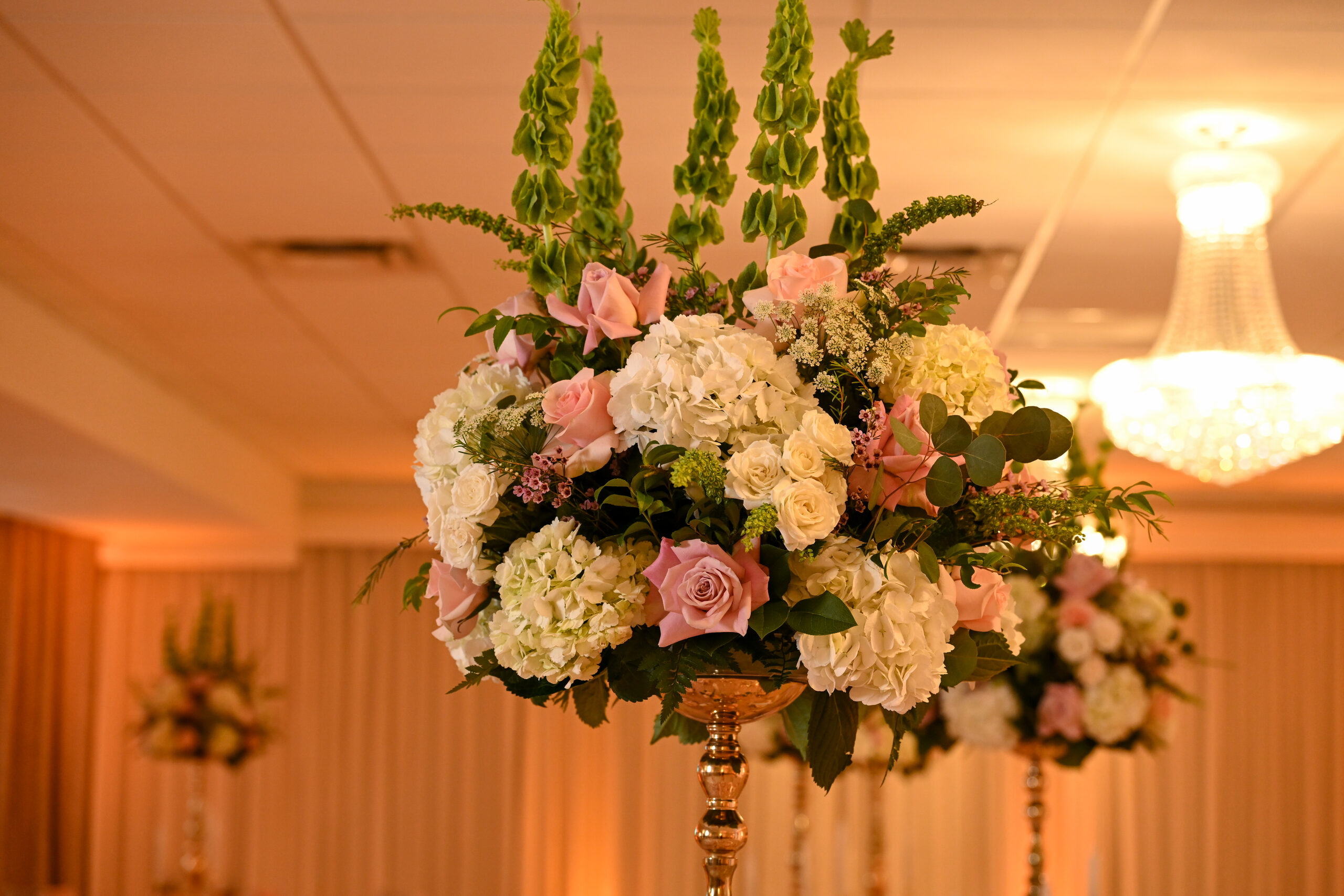 A tall floral centerpiece of hydrangea and blush roses