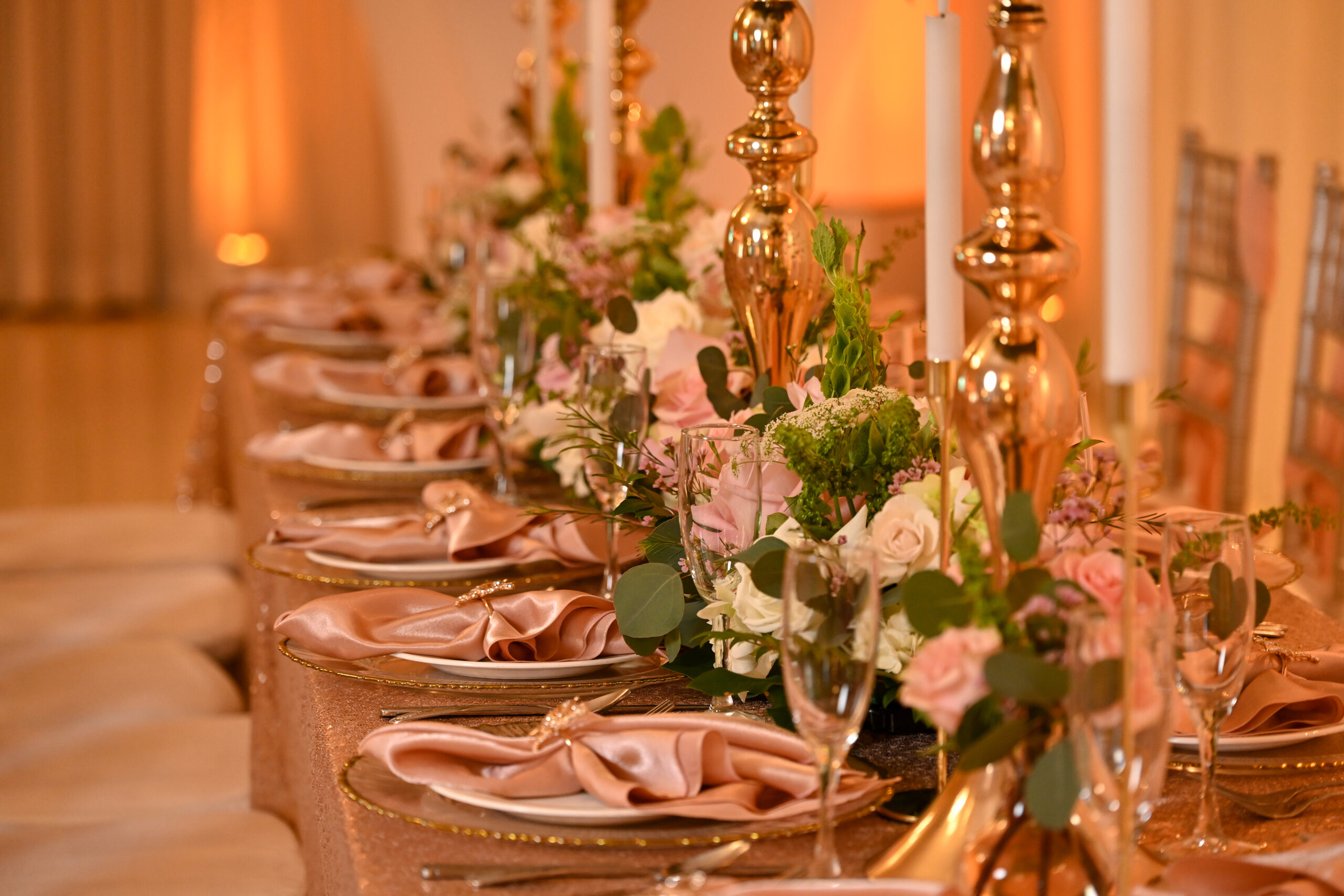 A long table set with gold candelabras and blush linens