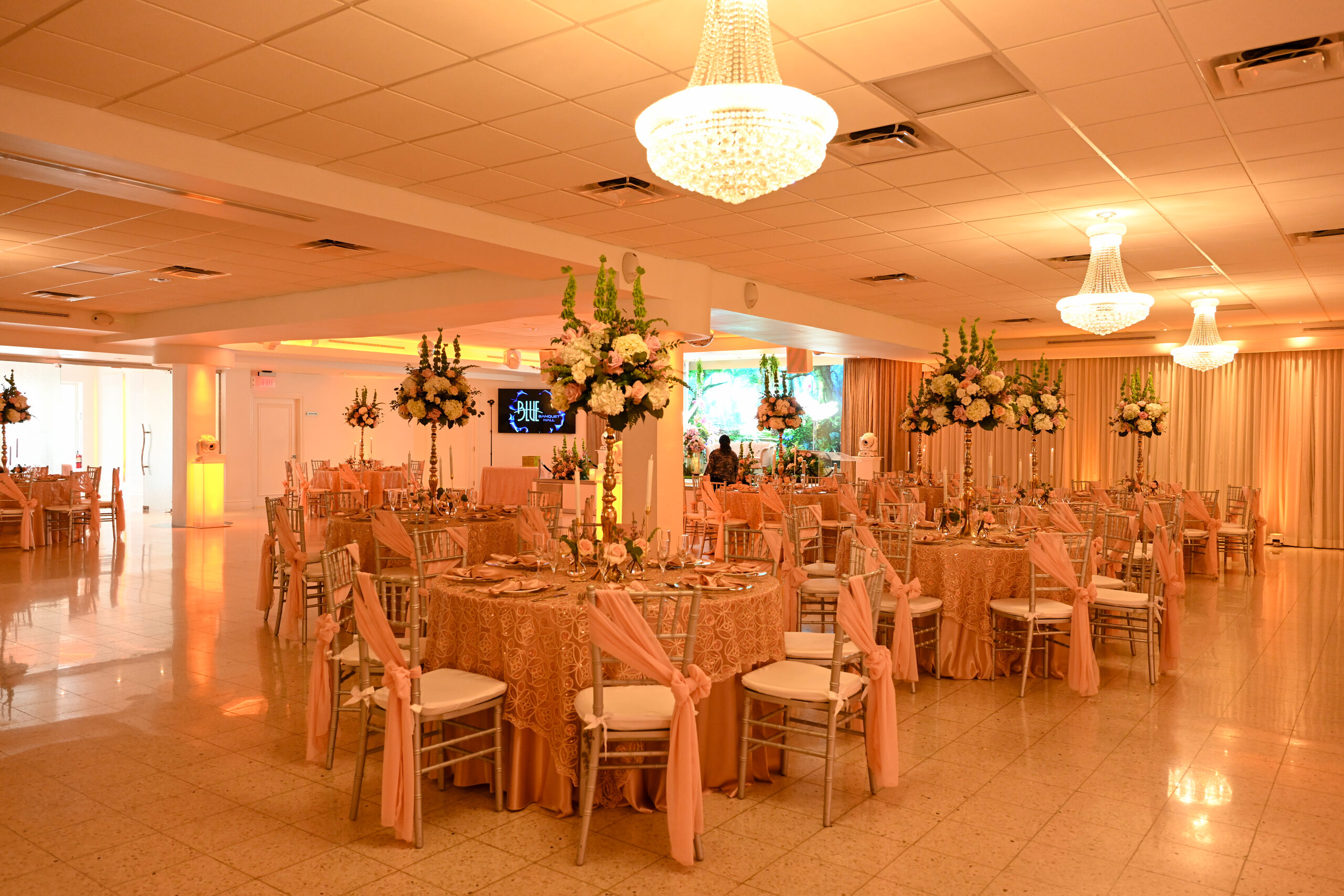 Round tables in blush linens under the hall's crystal chandeliers
